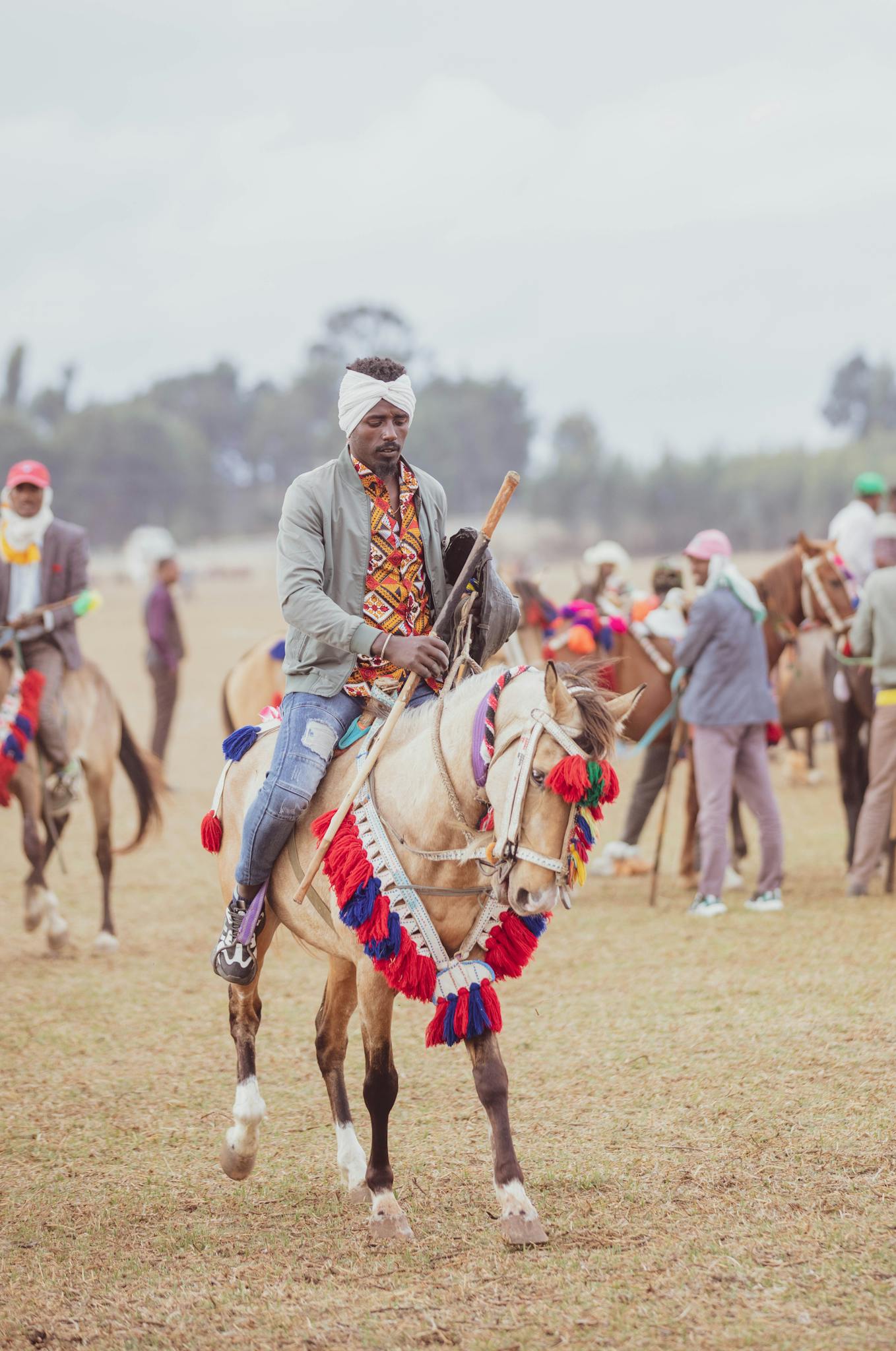 A man in colorful attire rides a decorated horse at a traditional equestrian event outdoors.